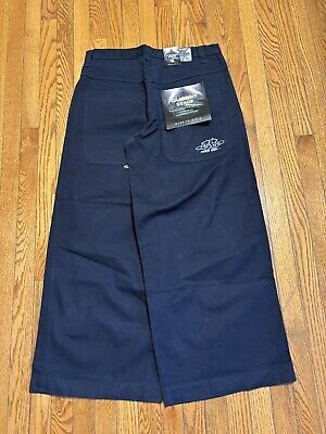 Dunkelblaue Baggy Jeans mit Etiketten auf Holzboden, bereit für die Bühne.