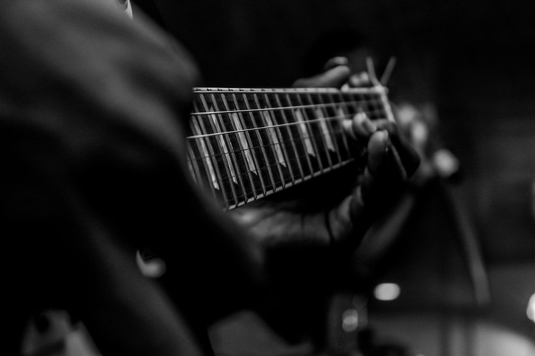 Schwarzweiß-Nahaufnahme einer Hand am Gitarrenhals beim Spielen