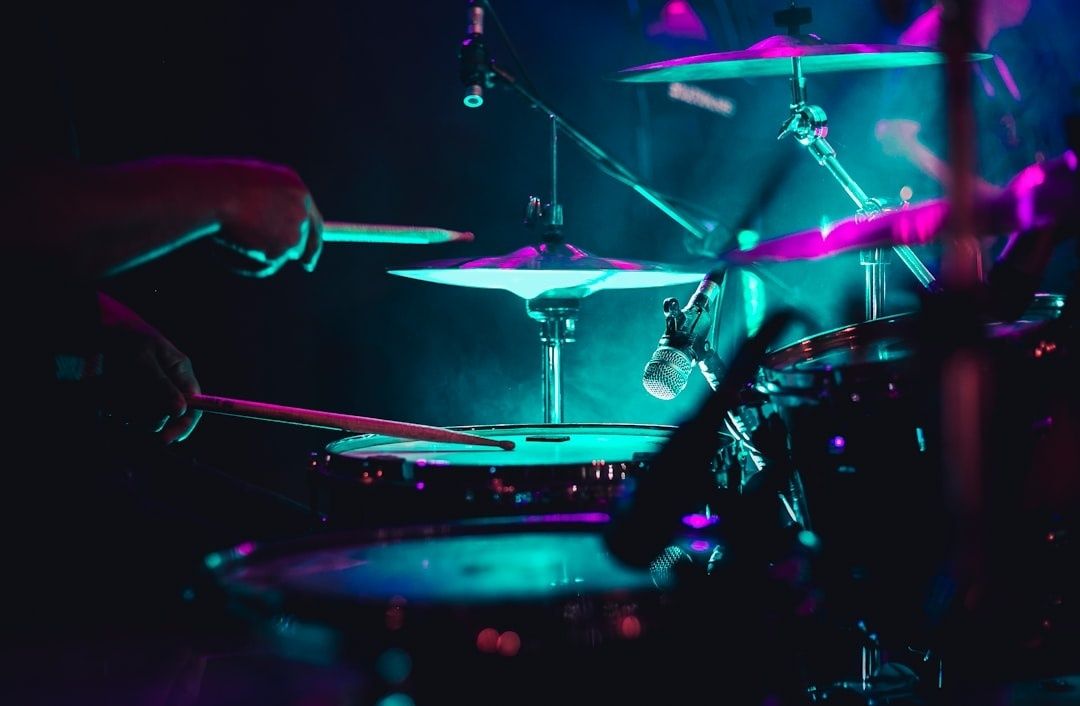 Schlagzeuger spielt ein Drumset bei farbigem Bühnenlicht